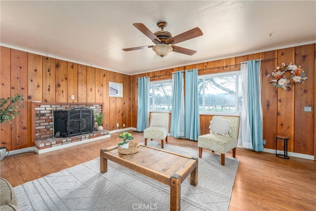 living room with ceiling fan, light wood-type flooring, a fireplace, and wood walls