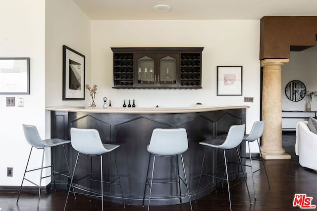 bar with decorative columns and dark hardwood / wood-style floors