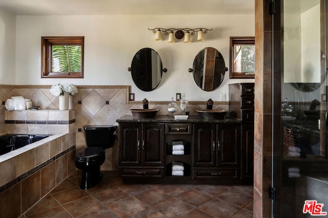 bathroom with tile patterned floors, tile walls, toilet, a bathing tub, and vanity