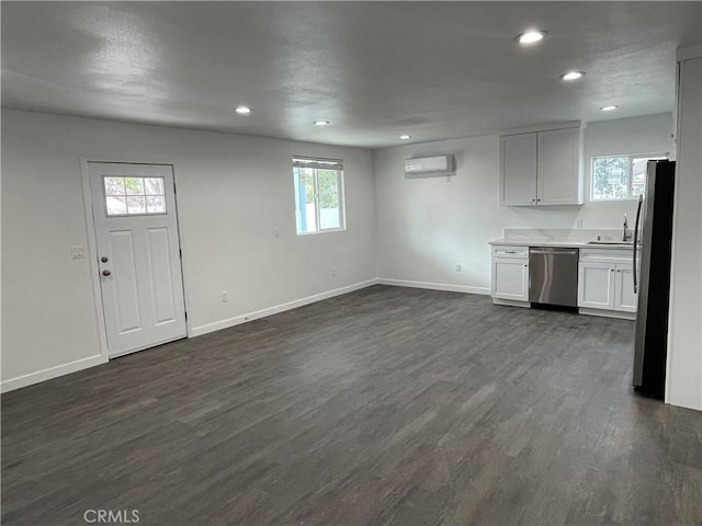 kitchen with dark hardwood / wood-style flooring, appliances with stainless steel finishes, white cabinets, and a wall unit AC