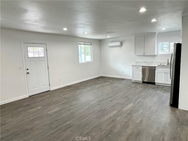 kitchen with sink, white cabinetry, a wall mounted air conditioner, dark hardwood / wood-style flooring, and stainless steel appliances