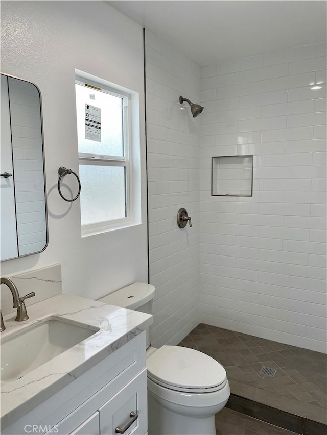 bathroom featuring tiled shower, vanity, and toilet