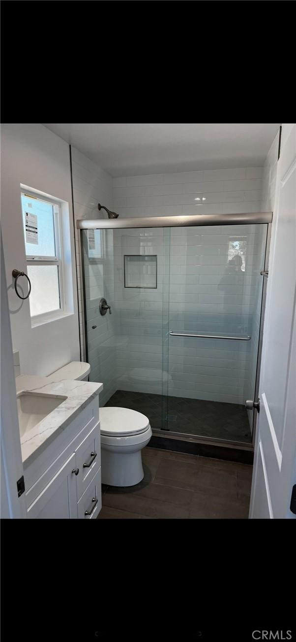 bathroom with vanity, wood-type flooring, a shower with shower door, and toilet