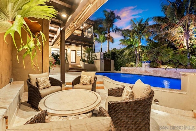 pool at dusk with pool water feature, an outdoor living space, and a patio