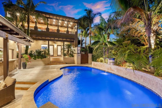 pool at dusk featuring a patio area