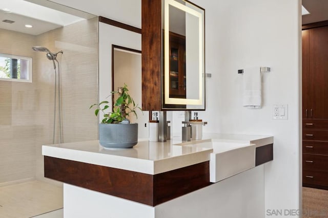 bathroom with vanity and tiled shower