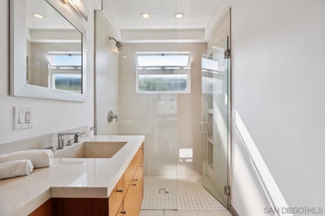 bathroom with a shower with shower door, vanity, and tile patterned flooring