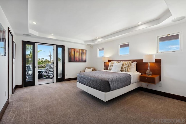 carpeted bedroom with access to exterior and a raised ceiling