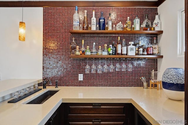 bar with sink, pendant lighting, and dark brown cabinetry