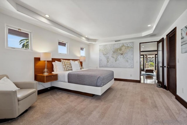 bedroom featuring light colored carpet and a tray ceiling