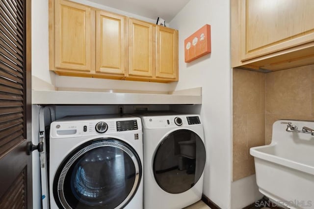 clothes washing area with cabinets, washer and clothes dryer, and sink