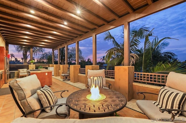 patio terrace at dusk featuring an outdoor fire pit and exterior kitchen