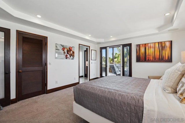 bedroom featuring carpet floors, access to exterior, and a tray ceiling