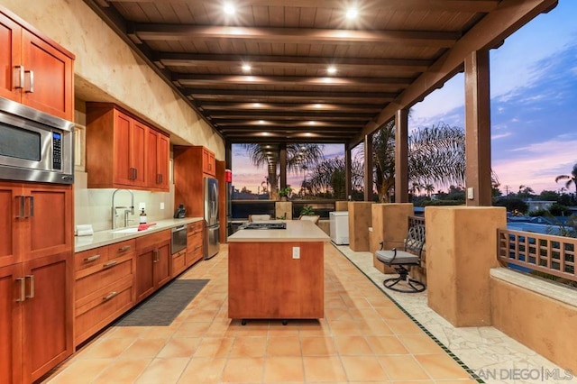 interior space featuring light tile patterned floors, stainless steel appliances, sink, and a center island