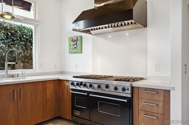 kitchen featuring sink, wall chimney exhaust hood, and range with two ovens