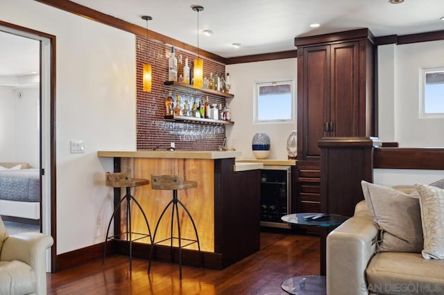 bar featuring pendant lighting, dark hardwood / wood-style floors, and ornamental molding