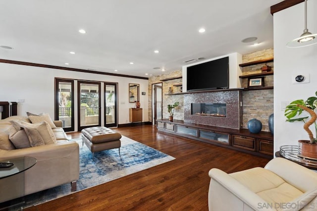 living room featuring crown molding, dark hardwood / wood-style floors, and a stone fireplace