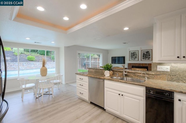 kitchen with a tray ceiling, dishwasher, sink, and white cabinets