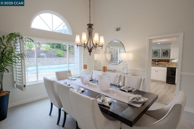 carpeted dining space featuring a high ceiling and an inviting chandelier