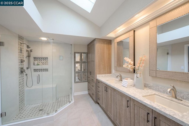 bathroom with tile patterned floors, vanity, vaulted ceiling with skylight, and a shower with door