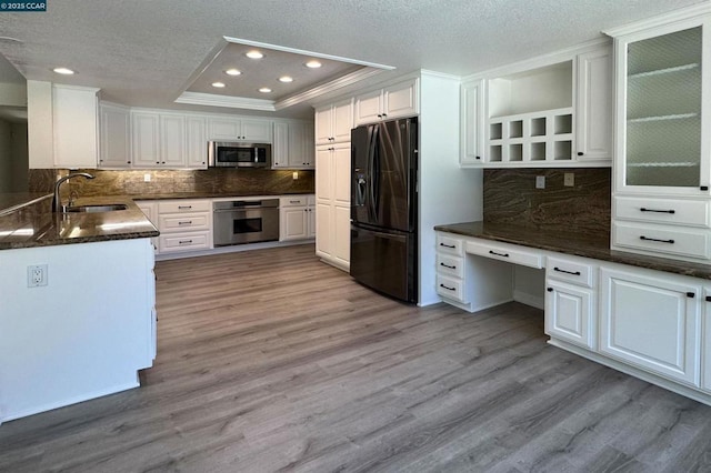 kitchen with sink, white cabinetry, built in desk, a raised ceiling, and stainless steel appliances