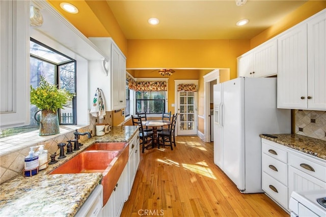 kitchen featuring backsplash, sink, white fridge with ice dispenser, and white cabinets