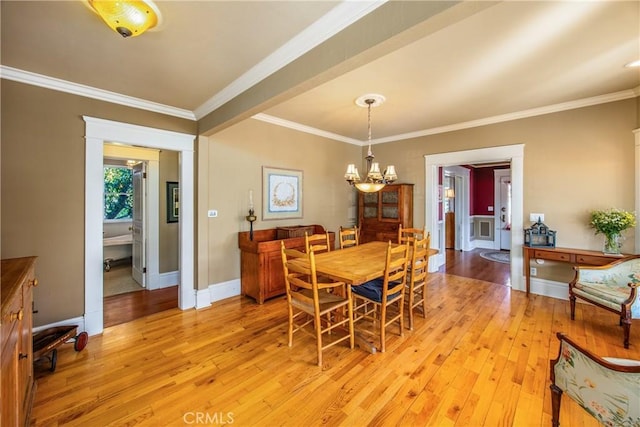 dining room featuring an inviting chandelier, ornamental molding, and light wood-type flooring