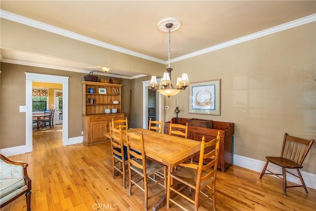 dining area featuring crown molding, light hardwood / wood-style floors, and a chandelier