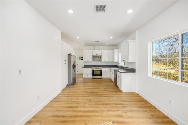 kitchen with stainless steel appliances, sink, light hardwood / wood-style flooring, and white cabinets