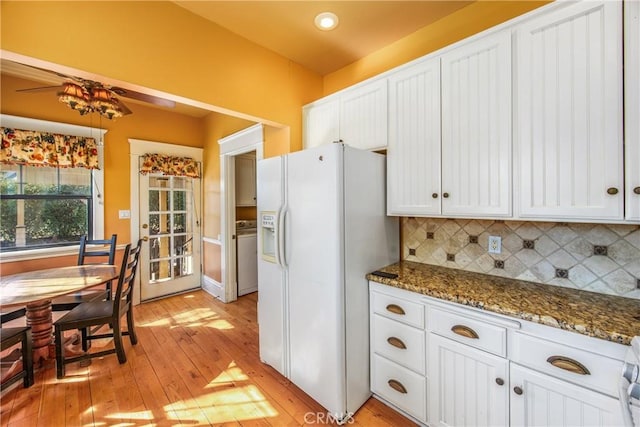 kitchen with tasteful backsplash, white cabinetry, dark stone countertops, washer / clothes dryer, and white refrigerator with ice dispenser