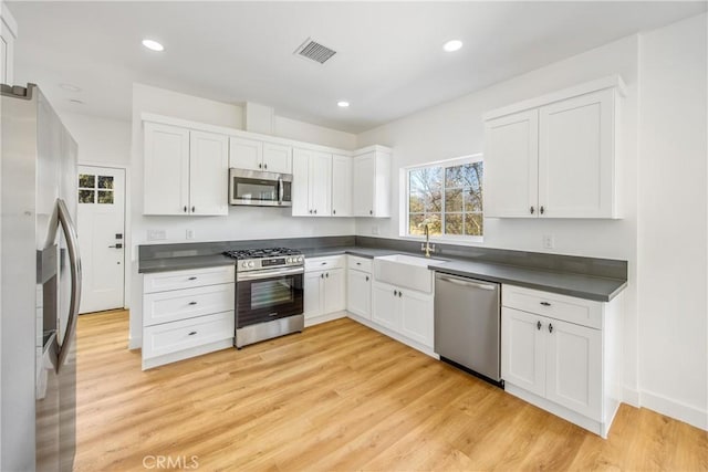 kitchen featuring sink, light hardwood / wood-style flooring, stainless steel appliances, and white cabinets