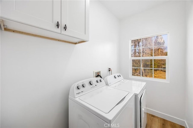 washroom featuring hardwood / wood-style flooring, washer and clothes dryer, and cabinets