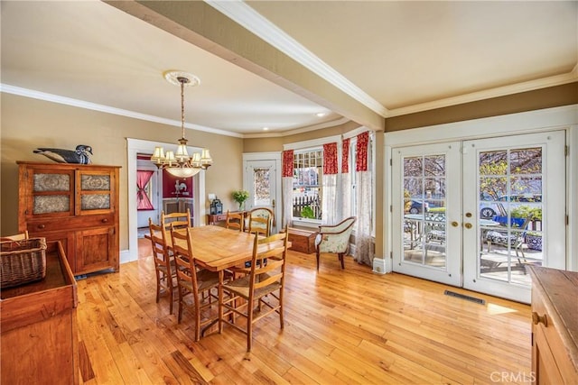 dining room featuring an inviting chandelier, ornamental molding, light hardwood / wood-style floors, and french doors