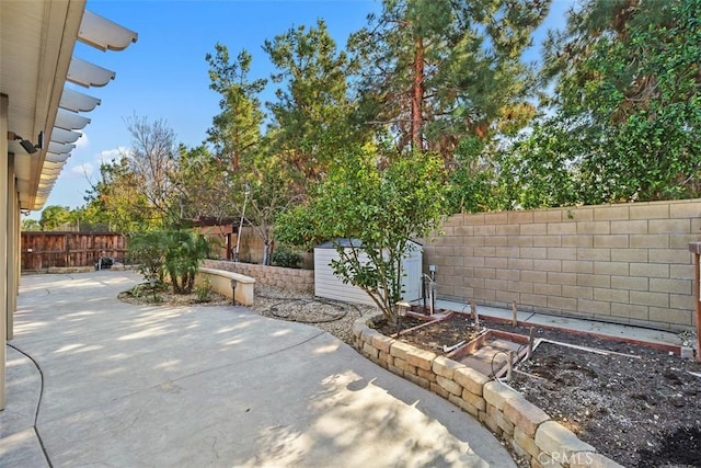 view of patio featuring a garden, a fenced backyard, a shed, and an outdoor structure