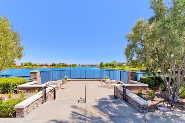 surrounding community with a patio area, fence, and a water view