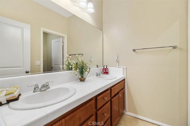 bathroom with baseboards, double vanity, a sink, and tile patterned floors