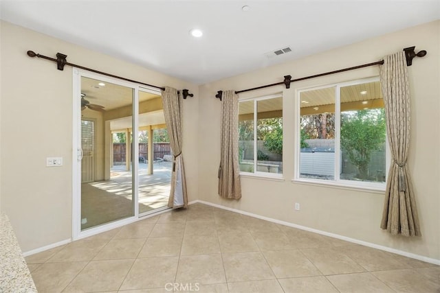 spare room featuring a healthy amount of sunlight, visible vents, baseboards, and tile patterned floors