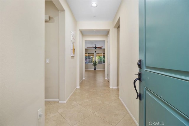 corridor with light tile patterned flooring and baseboards