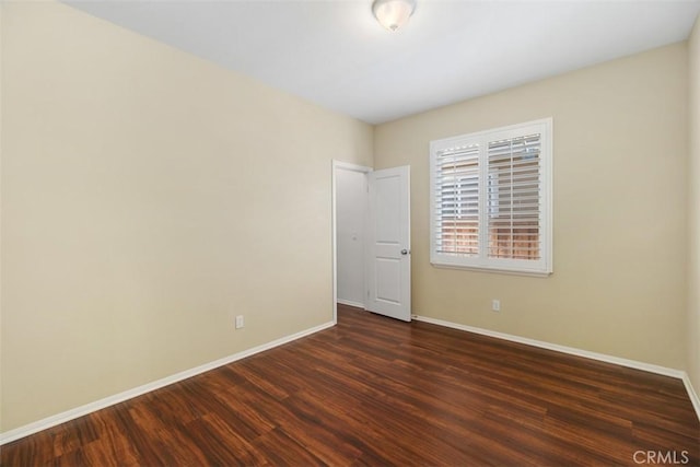 empty room with dark wood-type flooring and baseboards