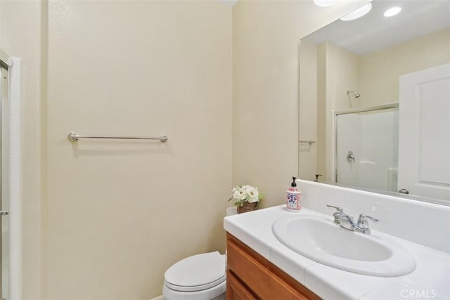 bathroom with a shower with shower door, vanity, and toilet