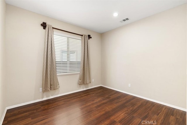 empty room featuring baseboards, visible vents, and wood finished floors