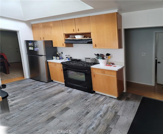 kitchen with black gas range oven, light wood-type flooring, and stainless steel fridge