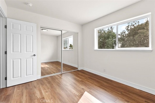 unfurnished bedroom featuring a closet, wood-type flooring, and multiple windows