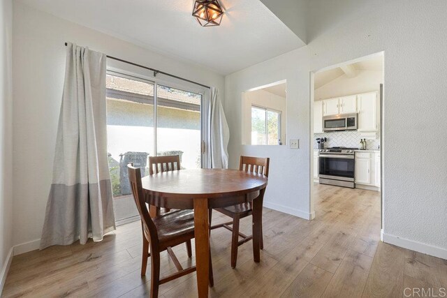 dining space with vaulted ceiling and light wood-type flooring