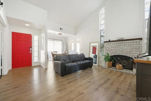 living room with a fireplace, hardwood / wood-style flooring, a wealth of natural light, and high vaulted ceiling