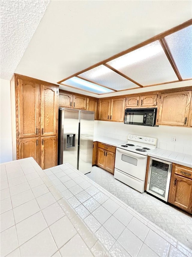 kitchen featuring stainless steel fridge, white range with electric stovetop, and tile countertops