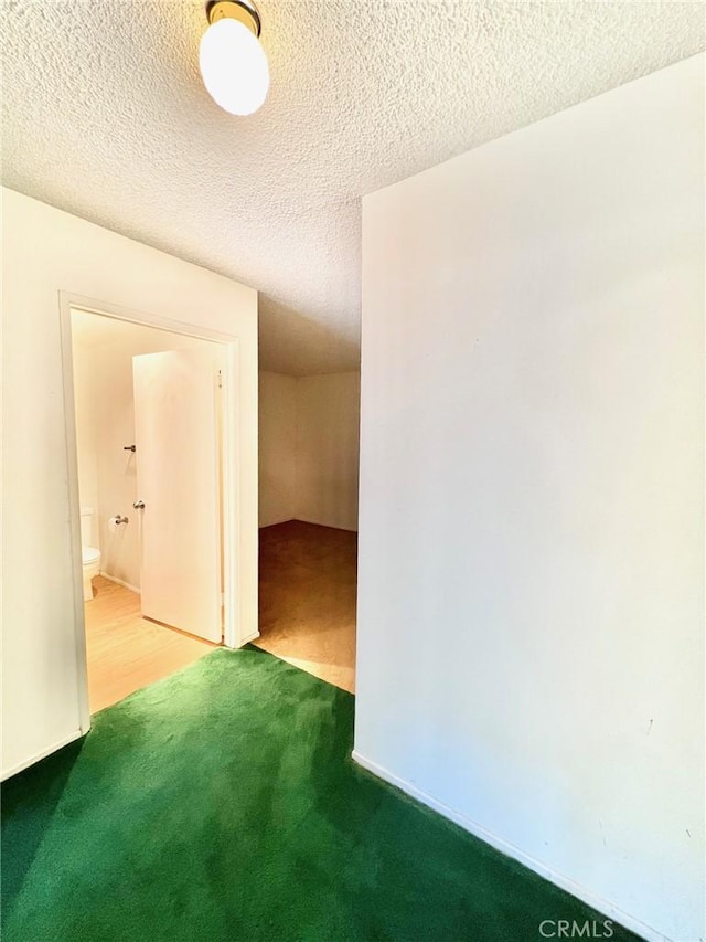 corridor with a textured ceiling and carpet flooring