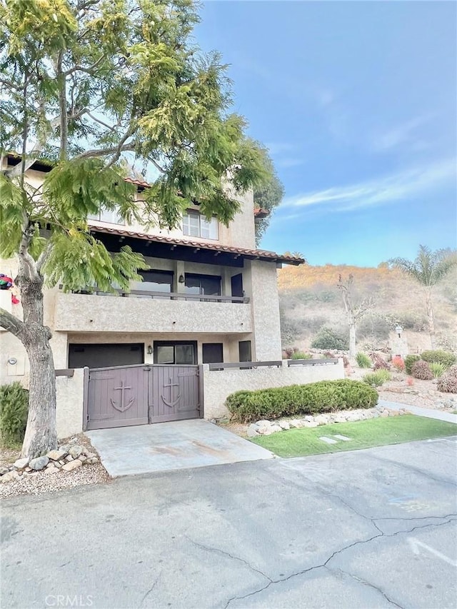 view of front facade featuring stucco siding, a gate, a fenced front yard, concrete driveway, and a garage