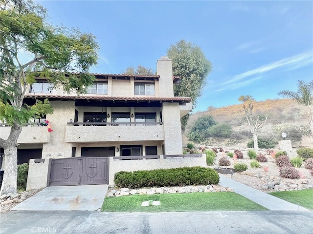 1 Cabrillo Dr, Avalon, CA 90704 - view of front of home featuring a balcony, a fenced front yard, stucco siding, a gate, and a chimney