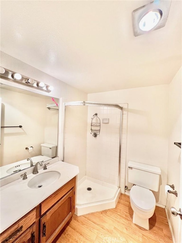 bathroom with vanity, toilet, hardwood / wood-style floors, and a shower with door